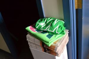 Two green Wildrose T-shirts sit on top of a stack of Edmonton Senior papers.