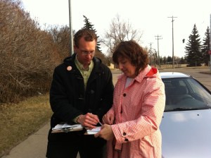 Marlin Schmidt out on the street examining a door-knocking list with a volunteer