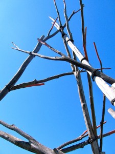 A tower made out of sticks stands out in front of a bright blue sky