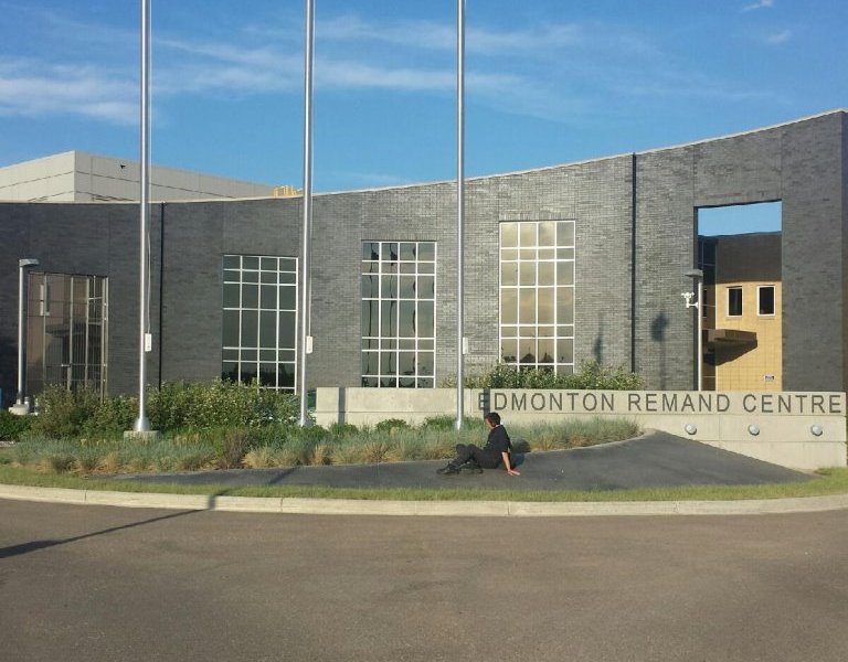 Chris sits on a landscaping strip outside the Edmonton Remand Centre