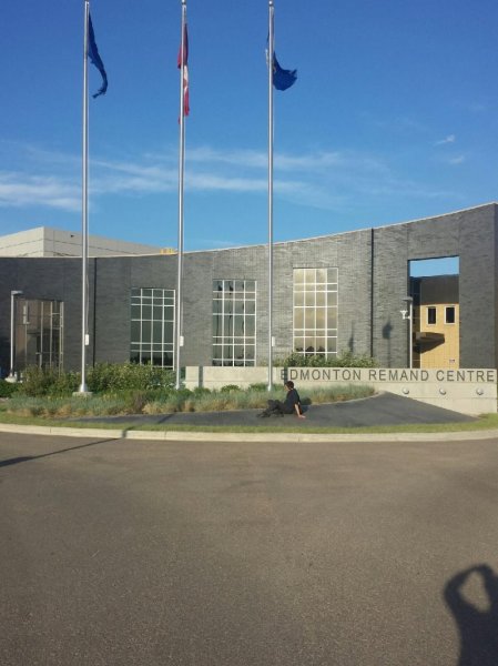 Chris sits on a landscaping strip outside the Edmonton Remand Centre